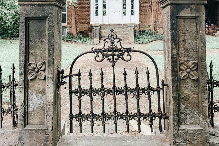 Black wrought-iron gate between stone pillars